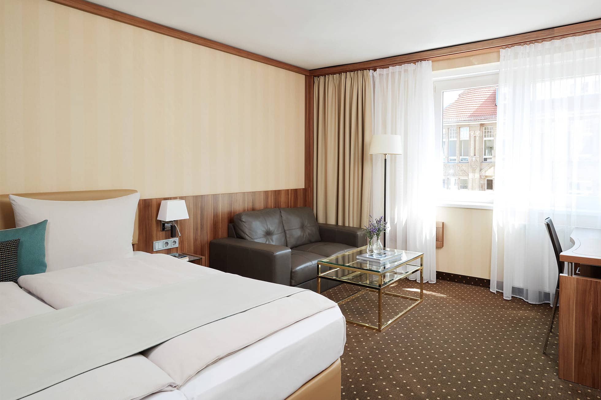 Living Hotel Berlin Mitte Deluxe Doppelzimmer Zimmereinblick auf das Doppelbett und die Couch