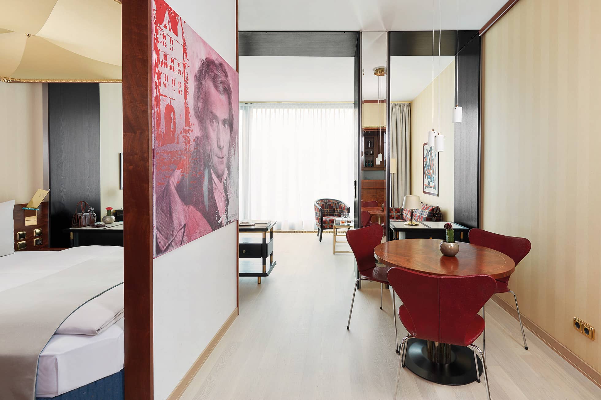 Geräumiges Serviced Apartment mit rundem Holztisch, Doppelbett und Wohnbereich