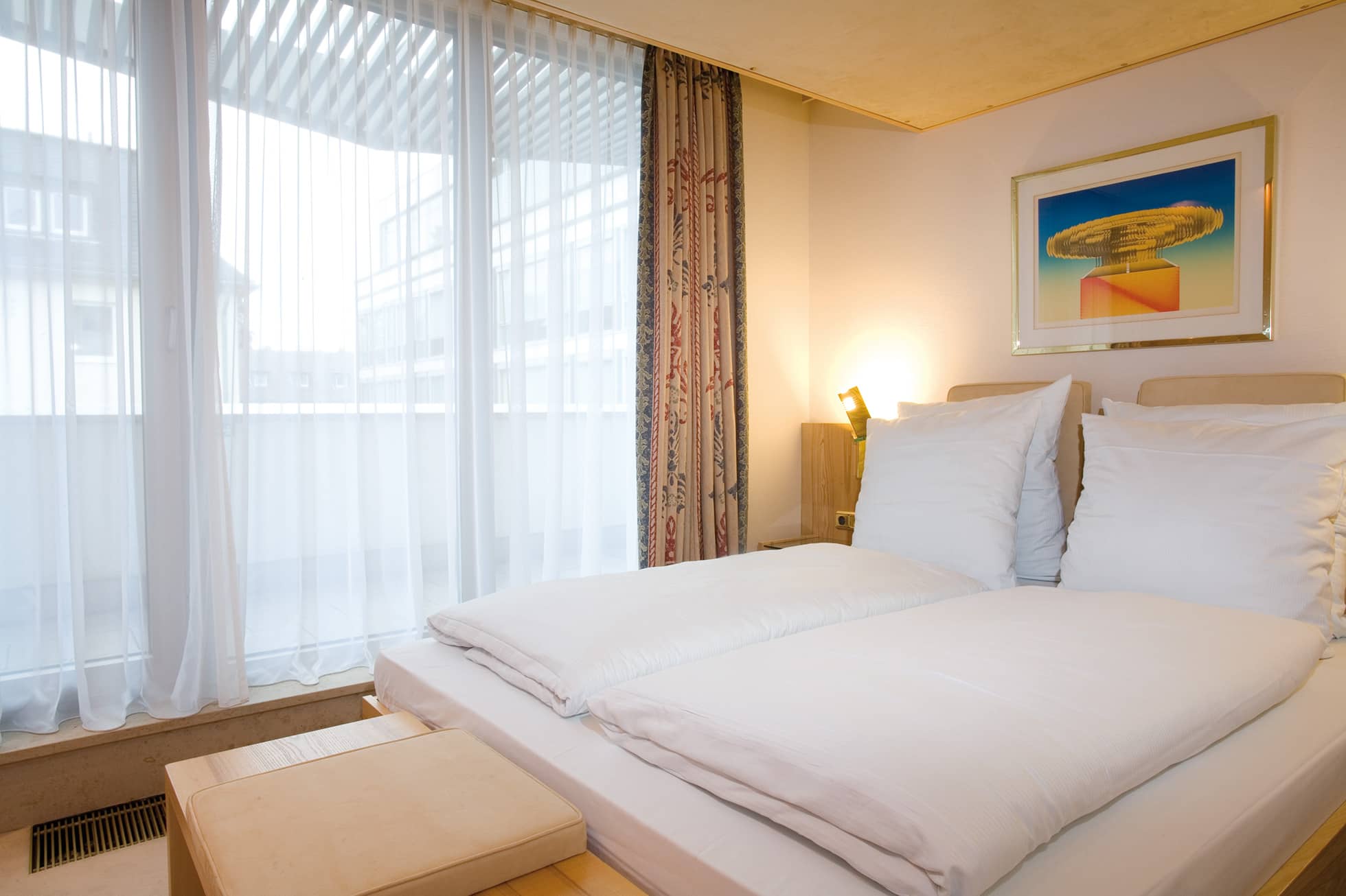 Living Hotel Kanzler Superior Doppelbett Bild von einem Doppelbett mit Sitzmöglichkeit am Fußende