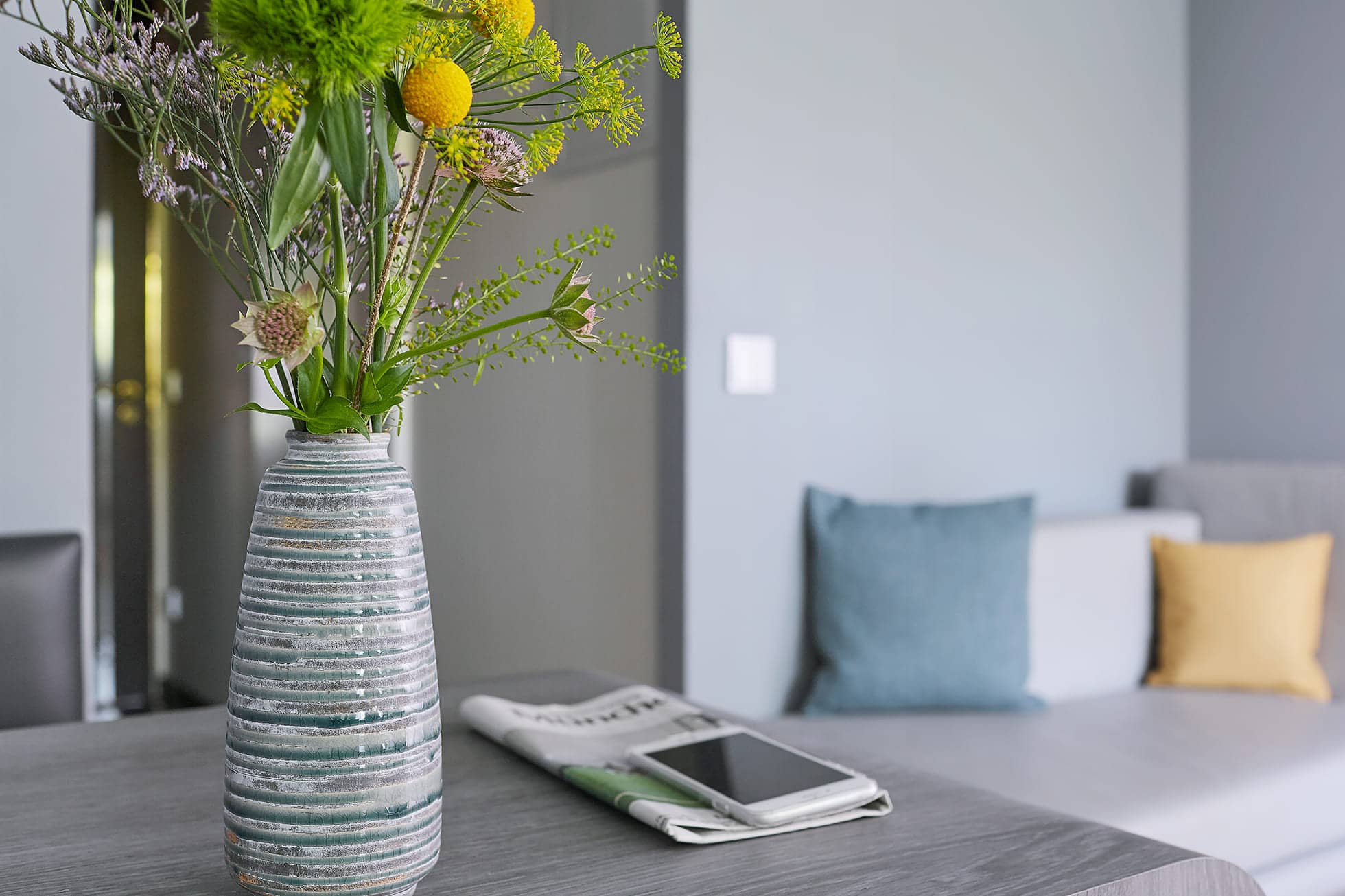 Living Hotel am Olympiapark Wohnen Blumenvase und Zeitung im Hotelzimmer