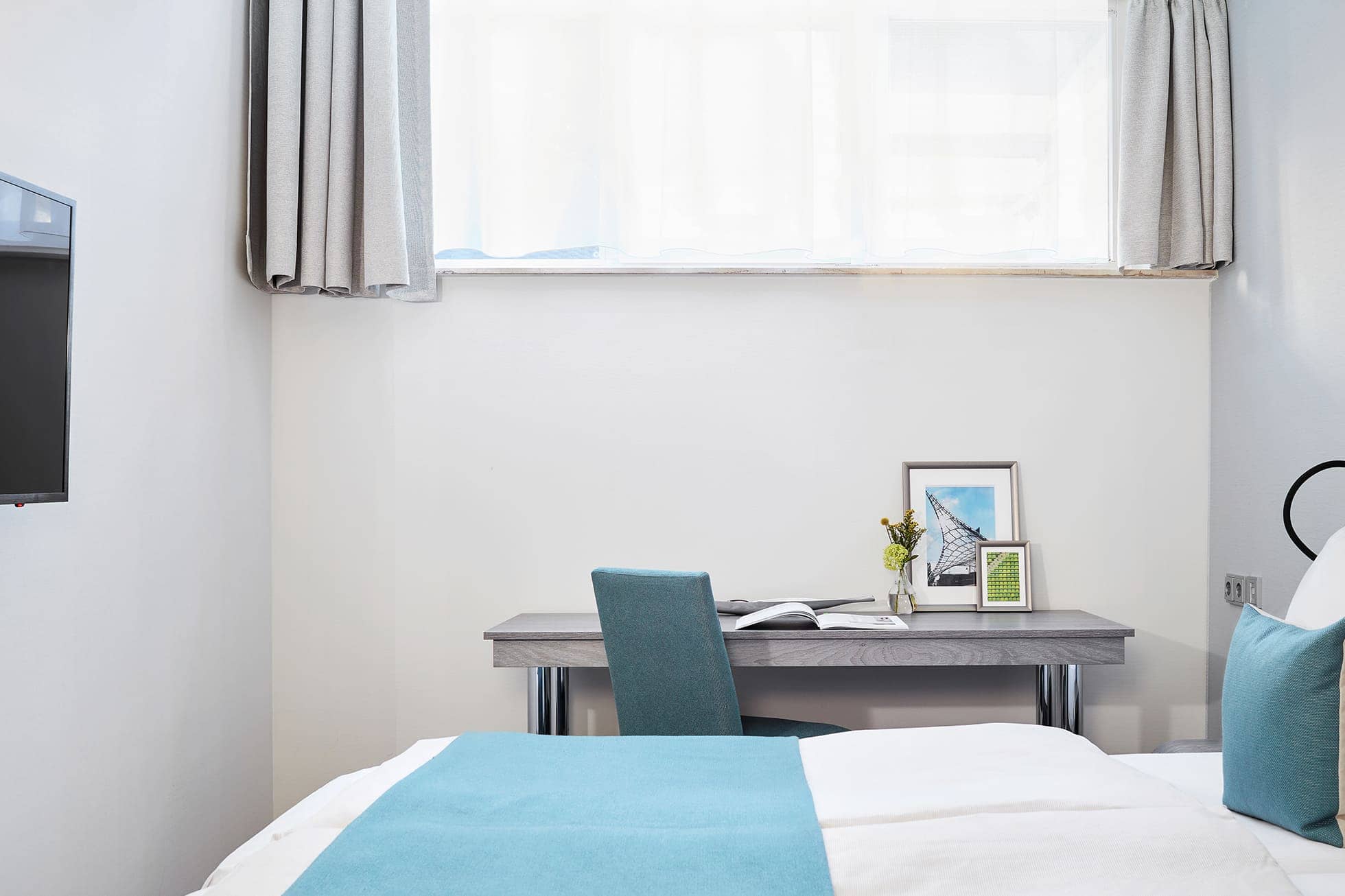 Living Hotel am Olympiapark Fitness Bett Bett mit Arbeitsbereich im Hintergrund
