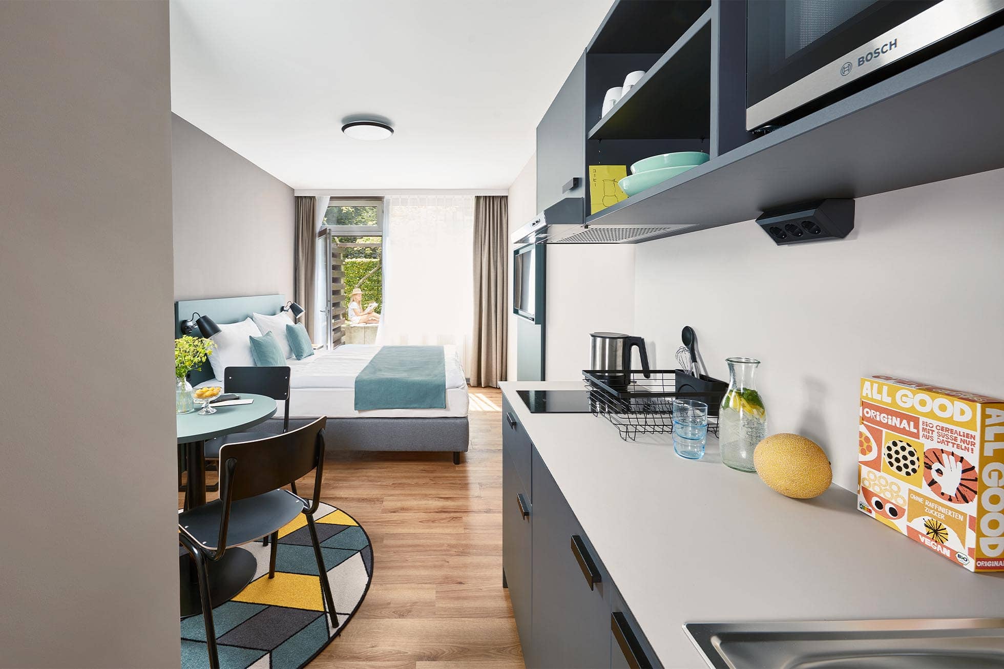Serviced Apartment mit offener Küche, rundem Esstisch mit Stühlen und Bett