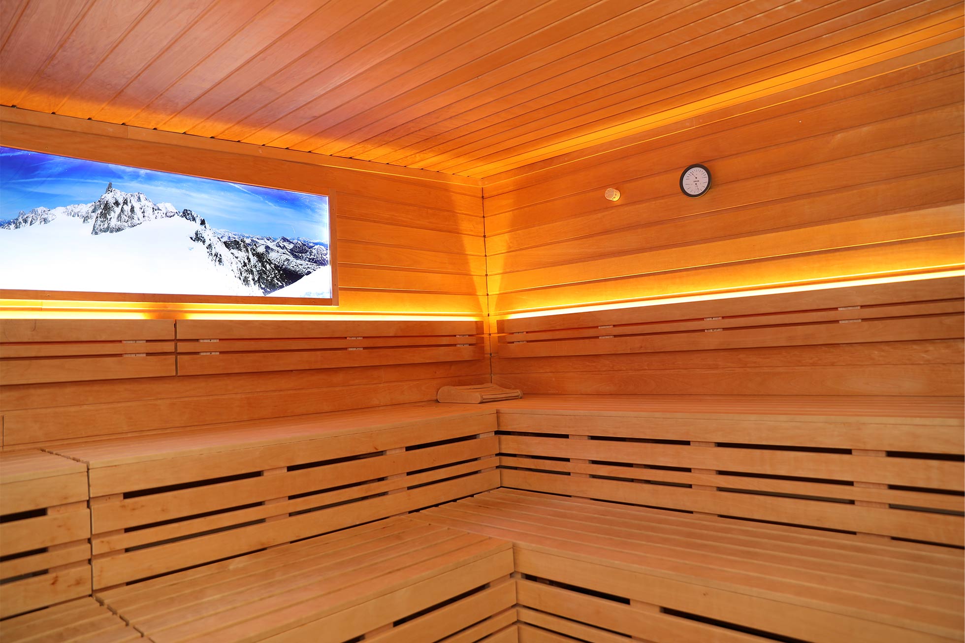 Hotel Sauna Bereich Innenraum der Sauna, hölzerne Sitzgelegenheiten mit leuchtendem Bergbild an der Wand