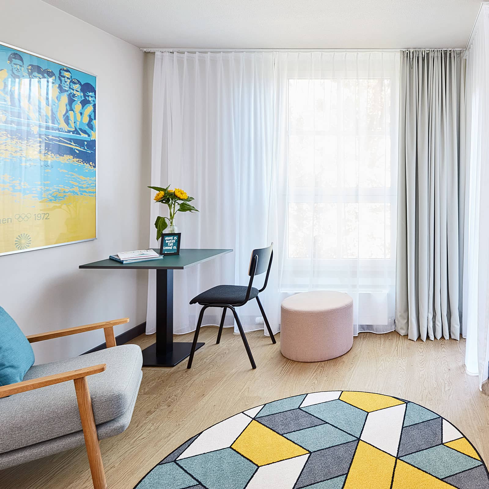 Neu renovierte Apartments gemütlicher Lesestuhl mit buntem geometrischen Teppich und einem kleinen Tisch mit Stuhl in der Ecke des Raumes