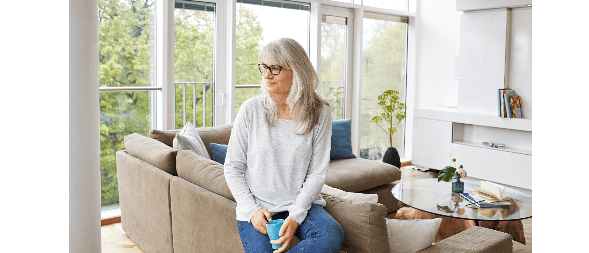 Temporäres Wohnen Living Hotels Serviced Apartments Frau sitzt gemütlich im Zimmer auf der Couch mit einer Tasse in der Hand