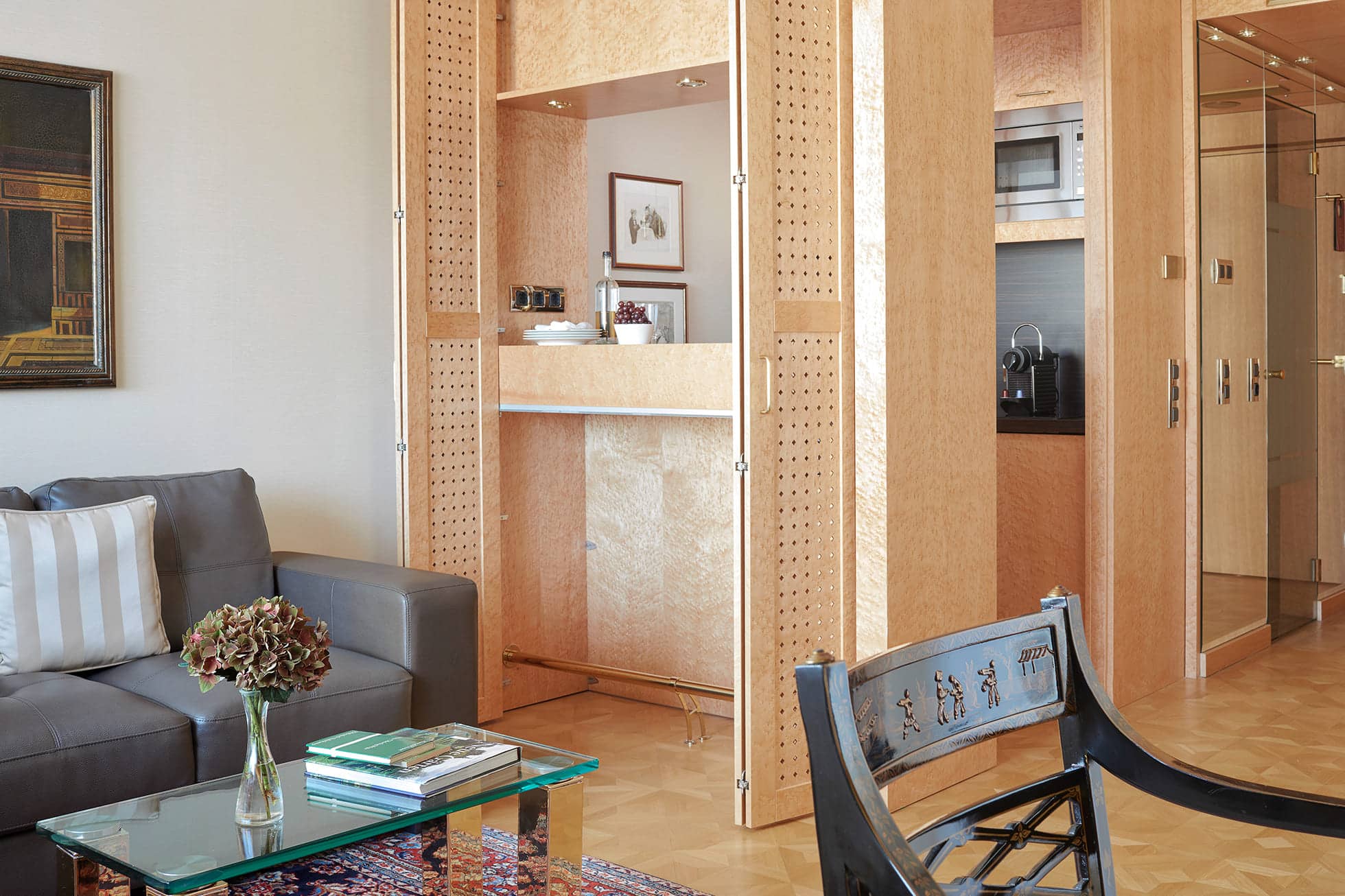 Serviced Apartment mit grauem Sofa, Sitzecke und integrierter Kitchenette.